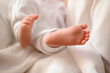 A baby's small leg during baptism on a white sheet