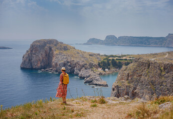 Wall Mural - Nice Happy Female Enjoying Sunny Day on Greek Islands. Travel to Greece, Mediterranean islands outside tourist season. Enjoying life and looking at the sea. Turquoise sea background.