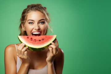 beautiful young woman eat juicy watermelon over green background.