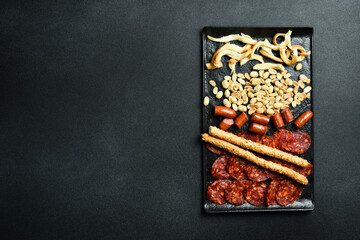 Wall Mural - Antipasto, Appetizers for beer: salami, cheese, nuts and sausages. On a dark background, close-up.