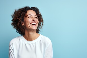Wall Mural - Portrait of a happy mature woman laughing and looking up against blue background