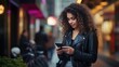Capture the essence of a young woman with curly hair and a black leather jacket, absorbed in using her mobile phone on the vibrant city street