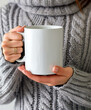 © henjon - Person wearing a grey sweater holding a white mug for a warm drink, cozy home concept..