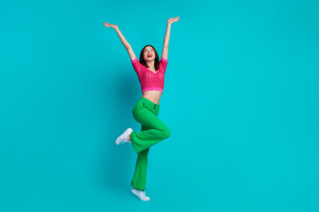 Poster - Full size photo of overjoyed girl wear pink top retro trousers raising palms up look empty space isolated on blue color background