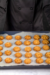 Shortbread Cookies. The Confectioner in Black Uniform Holds in his Hands a Baking Tray with Shortbread Cookies