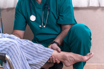 Orthopedic doctor examines and checking knee's elderly woman patient on wheelchair at hospital