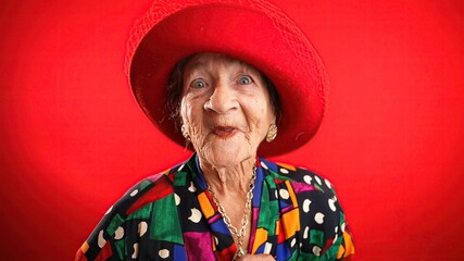 Poster - Saying WOW, a happy fisheye portrait caricature of funny elderly woman with red hat isolated on red background.