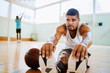 © Marko Geber - Young man stretching before playing basketball in an indoor basketball gym