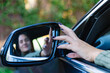 Hand of woman driver adjusting the side view mirror of her car. Selective focus. Transportation, travel and road safety concepts