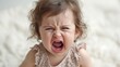 A young child is visibly upset and crying, expressing distress or displeasure with a scrunched face.