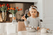 © Maria - happy excited kid girl baking cake for Easter emotional child cook dessert present for mother day in white sunny kitchen Home bakery. Bottle of milk, eggs, flour are on the table