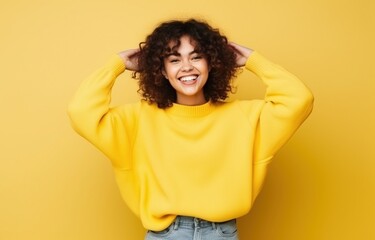 Smiling young woman with curly hair wearing yellow sweater