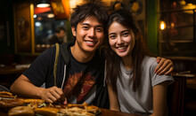 Young Asian Couple Enjoy Eating Together In A Pub Or Restaurant.
