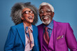 Cheerful laughing African American fashion senior man and asian woman having fun on studio background. Senior couple feeling vibrant in colorful casual clothing. Mature enjoying their golden years.