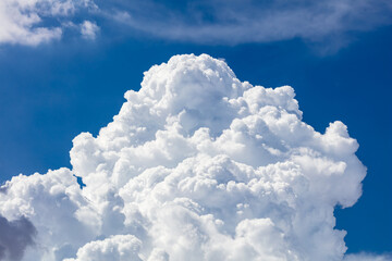 closeup of billowy cumulus clouds. wispy clouds, deep blue sky in background.