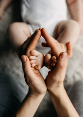 Wall Mural - Mother hands holding a newborn child's feet, symbolizing love and care.