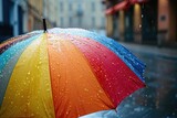 Fototapeta Tęcza - Opened umbrella in vibrant colors on a rainy street
