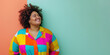 © Mirador - A woman beams with happiness in a vibrant, multicolored shirt against a dual-tone background