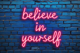 Fototapeta  - Empowering Neon Message on Brick Wall. 'Believe in Yourself' neon sign offers inspiration against a textured blue backdrop