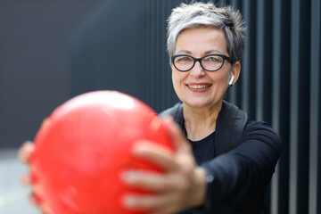 Wall Mural - Mature woman engages in outdoor sports, playing with a ball, embodying an active and healthy lifestyle.