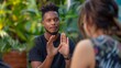Couple talking in a garden or at a restaurant terrace, handsome black man using body language to express himself with his hands up, describing or miming something, kindly looking at a caucasian woman