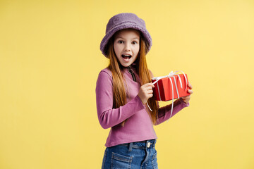 Wall Mural - Portrait of attractive little girl holding red gift box, feeling happy isolated