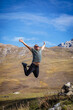 © ЮРИЙ ПОЗДНИКОВ - A man happily jumps on the top of a mountain, exhilarating the mesmerizing scenery and his achievement