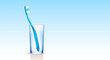 A blue toothbrush in a transparent glass, on a gradient blue background. Dental concept. Copy space.