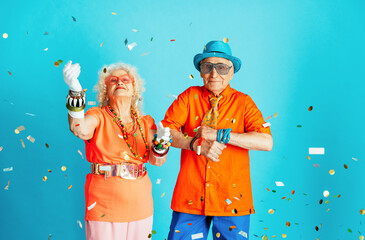 Wall Mural - Beautiful senior old couple wearing fancy party clothes acting in studio on a colored background. Conceptual image about third age and seniority, old people feeling young inside.