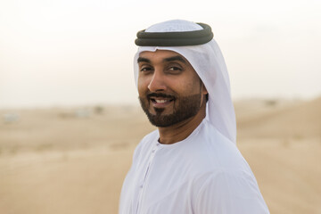 Wall Mural - Business men wearing traditional uae white kandura spending time in the desert of Dubai.