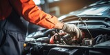 Fototapeta Tęcza - Car mechanic wearing orange jumpsuit fixing a car engine