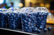 Plastic glass with lid closed with blueberries on shelf in store. Healthy ready to go snack to take away from berries in cup