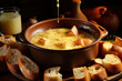 Cheese fondue with pieces of bread on large platter on dark background
