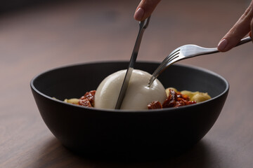 Wall Mural - Closeup of pesto conchiglie with sundried tomatoes and cutting burrata cheese served in black bowl