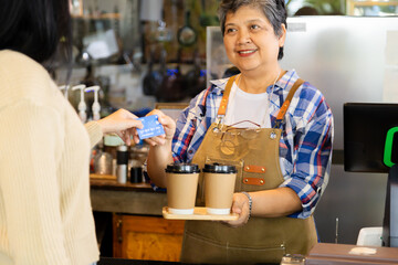 Asian senior people lifestyle small business start-up show credit card cashless payment by customers, elderly pensioner female open cafe coffee shop restaurant, healthy aging woman working as barista