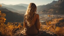Young Woman With Long Blond Hair Sitting On A Rock And Looking At The Sunset