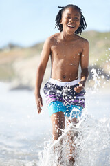 Wall Mural - Portrait, African boy and happiness on beach in water for adventure, holiday or vacation in summer. Happy kid, face and smile outdoor in nature for break, experience or playing in ocean with splash