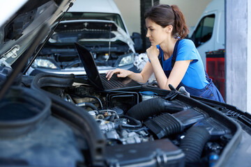 Female auto mechanic uses a laptop for work