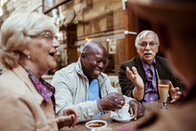Diverse elderly tourist sitting in city outdoor cafe