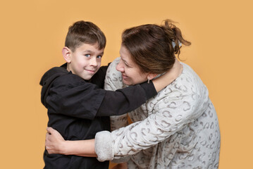 Wall Mural - Young boy hugs mother tenderly at home, good relationship between school boy and his mother, they are smiling and talking