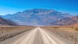 An unpaved road leads straight to the high mountains of Death Valley.