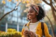 Smiling happy cute African teen girl student holding cellphone looking away with smartphone technology device in hand walking in college park outside using apps on mobile phone, Generative AI