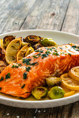 Wall Mural - Fried salmon steak and garlic, brussels sprouts and lemon served on wooden table