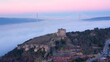 Yoros Castle looks down on Istanbul ridges on sunset. Dense fog bank blankets the lower elevations of Bosphorus. Yavuz Sultan Selim Bridge in the background. Drone point of view of Turkey