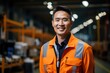 Portrait of a smiling Asian man in an orange jumpsuit in a warehouse