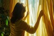 A woman is seen looking out of a window with yellow curtains. This image can be used to depict curiosity, anticipation, or a peaceful moment of reflection.