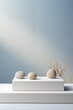 Three zen stones balanced on a white podium with a serene blue gradient background