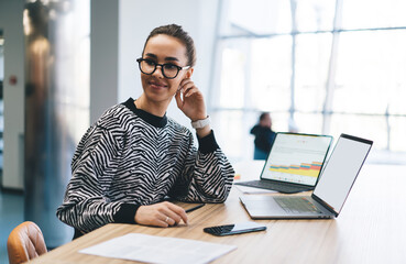Positive young female programmer working over table with laptop