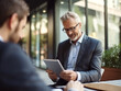© domi002 - A businessman in a meeting confidently using a digital tablet to manage and present information.