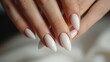 Close-up of hands showcasing long white stiletto-shaped manicured nails with a shiny finish.